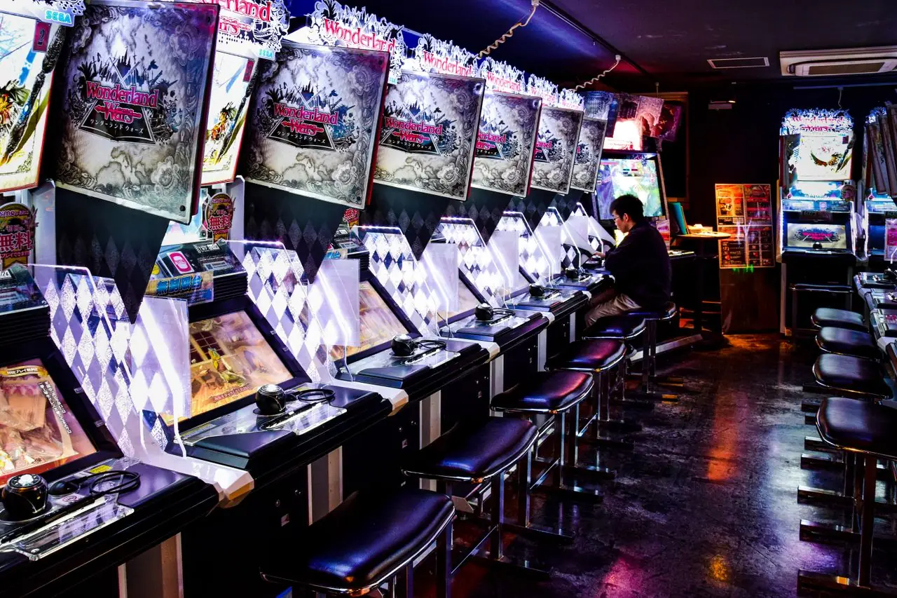 Rows of seated video game cabinets inside a Tokyo arcade at night