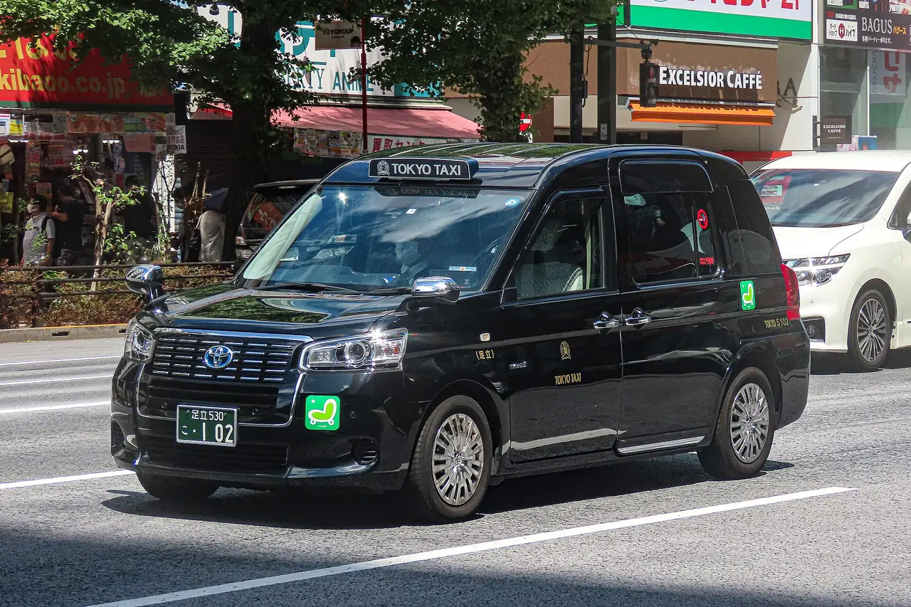 Black Toyota JPN Taxi cab driving along a Tokyo street
