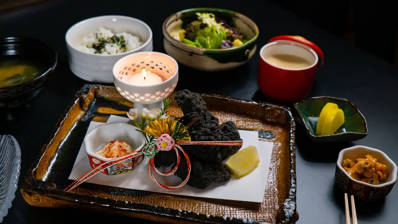 Formal Japanese dinner tray with rice, soup, pickles and small seasonal dishes by candlelight
