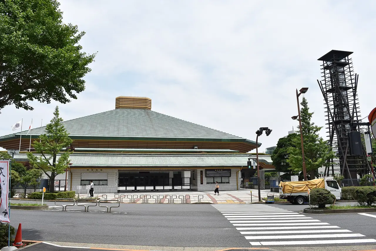 The green roof of the Ryogoku Kokugikan sumo arena beside its drum tower