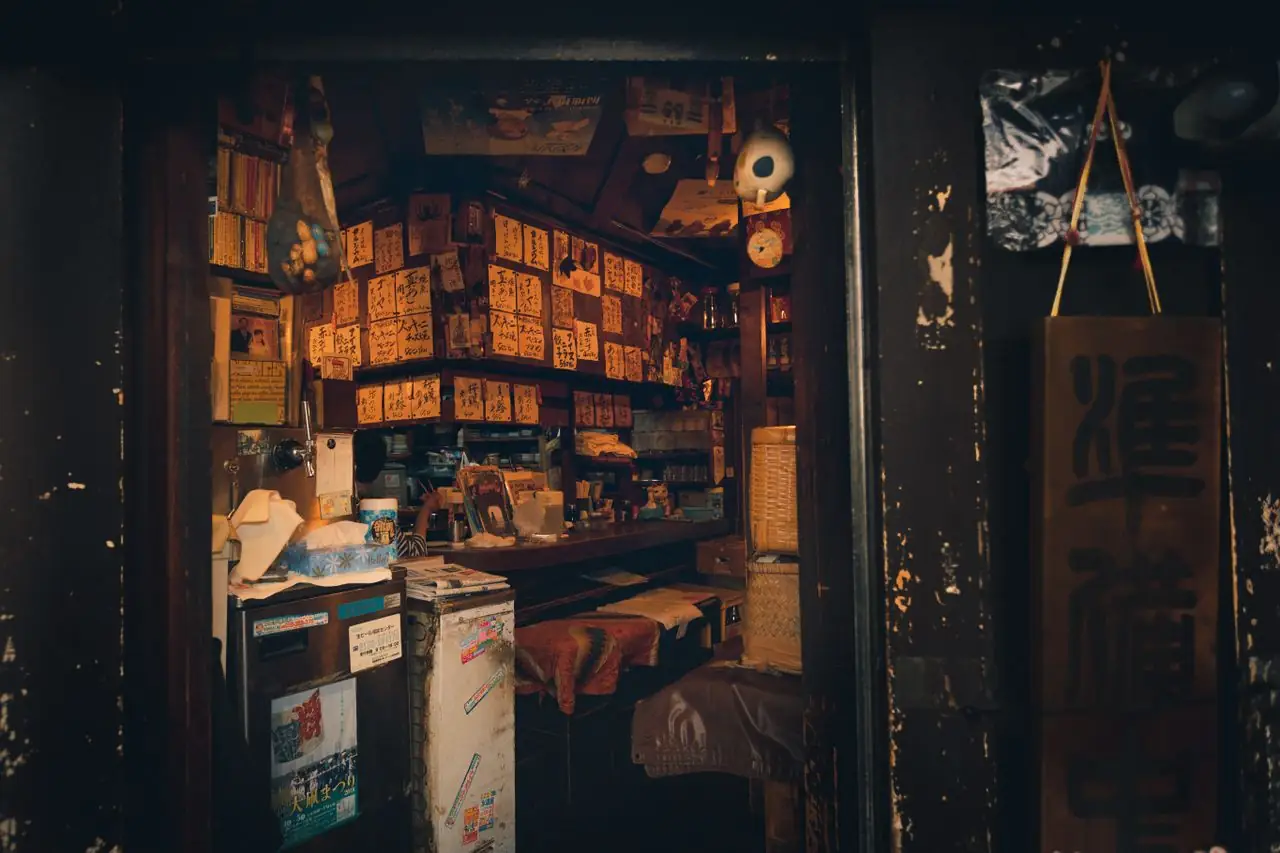 Handwritten Japanese menu slips covering the walls of a tiny izakaya with no English