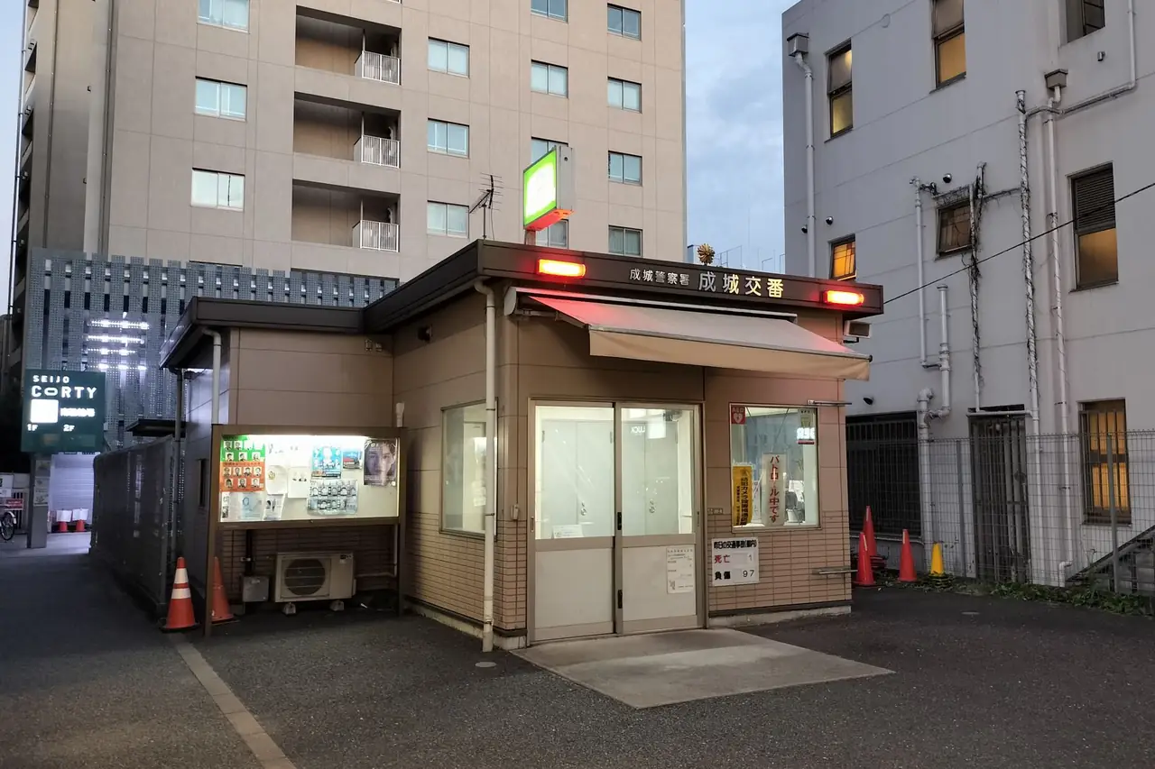 Red lamps lit outside the Seijo koban police box near Seijogakuen-mae Station at dusk