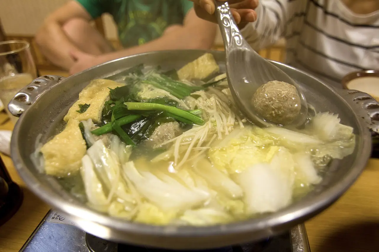 A pot of chanko nabe with chicken meatballs, Chinese cabbage, fried tofu and enoki