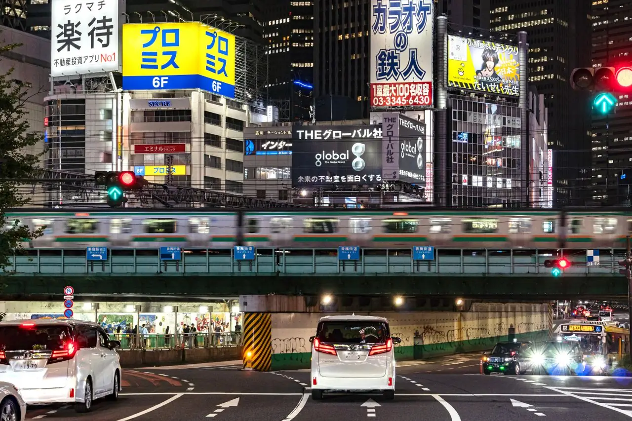A JR commuter train crossing the overpass above Ome-kaido in Shinjuku at night