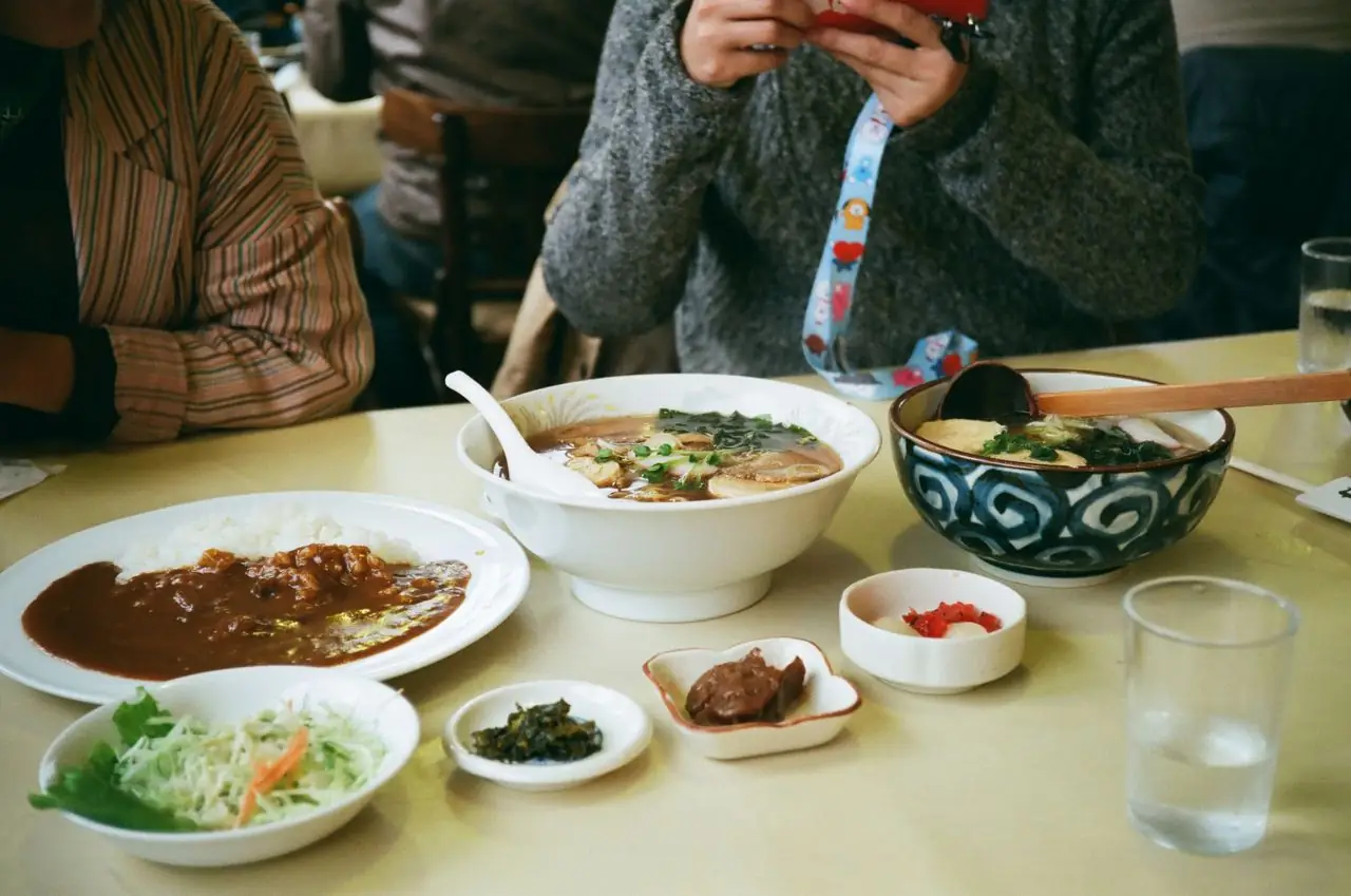 Ramen, curry rice and small side dishes shared across a casual Japanese lunch table
