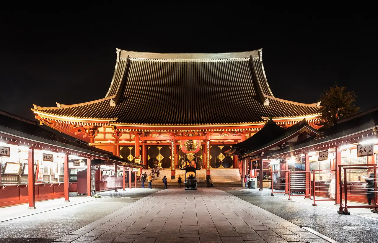 Sensoji main hall lit up at night above a nearly empty temple courtyard