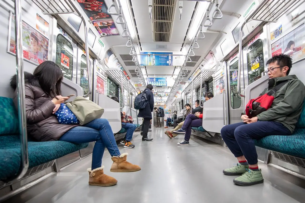Passengers sitting quietly on their phones inside a Tokyo commuter train car