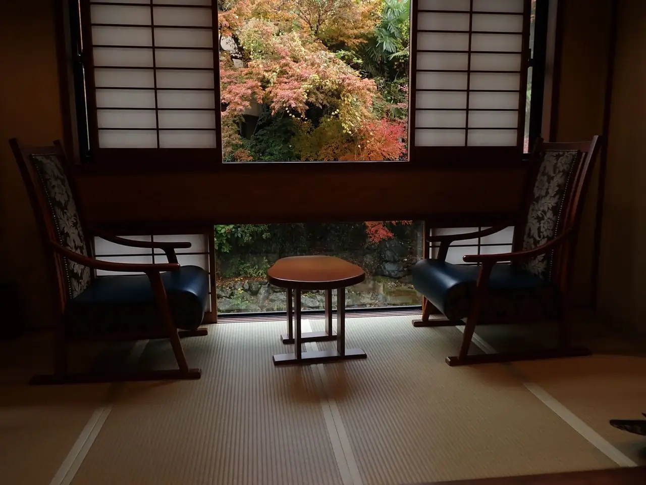 Window seating in a tatami ryokan guest room looking out on autumn maples