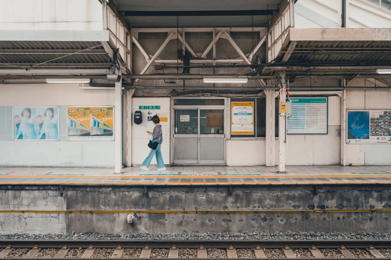 A woman walking alone along a quiet train platform in Tokyo