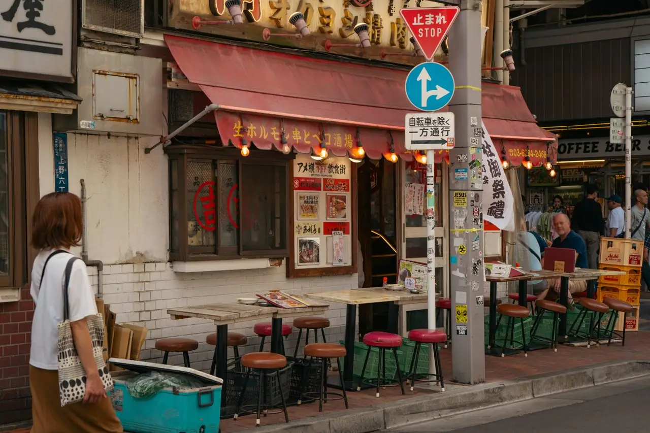 Stools and tables set out on the pavement in front of a Tokyo izakaya