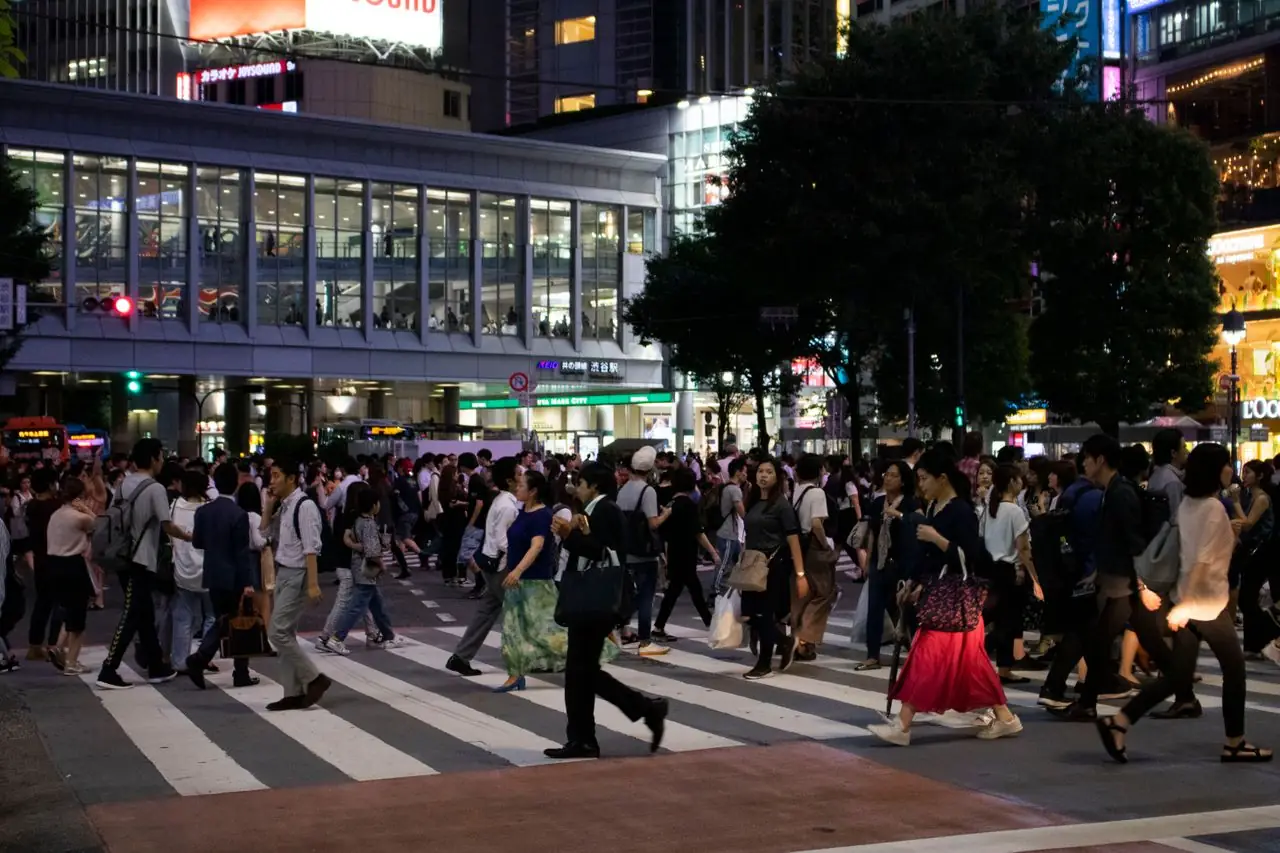 Crowds of pedestrians crossing Shibuya Crossing at dusk