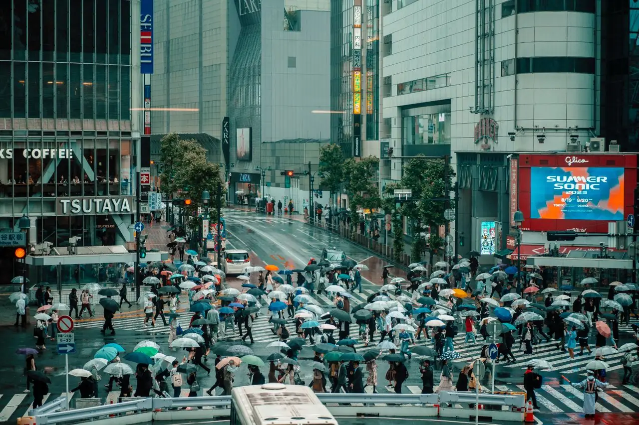 Crowds with umbrellas crossing Shibuya Crossing on a rainy day