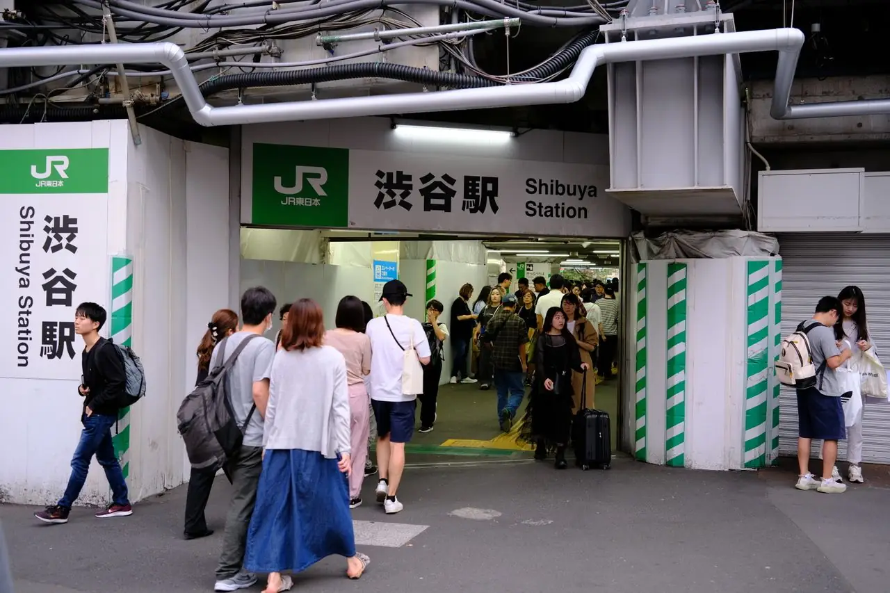 Travelers streaming into the JR entrance of Shibuya Station in Tokyo