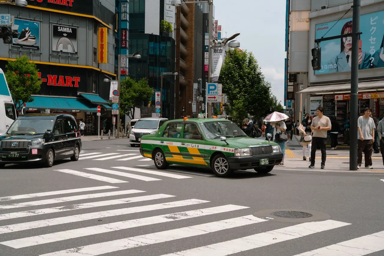 A green Tokyo taxi and pedestrians at a busy city crossing