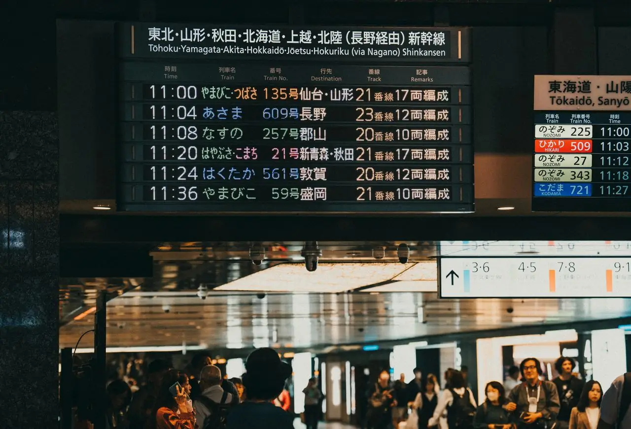 Shinkansen departure board above travelers in the concourse at Tokyo Station
