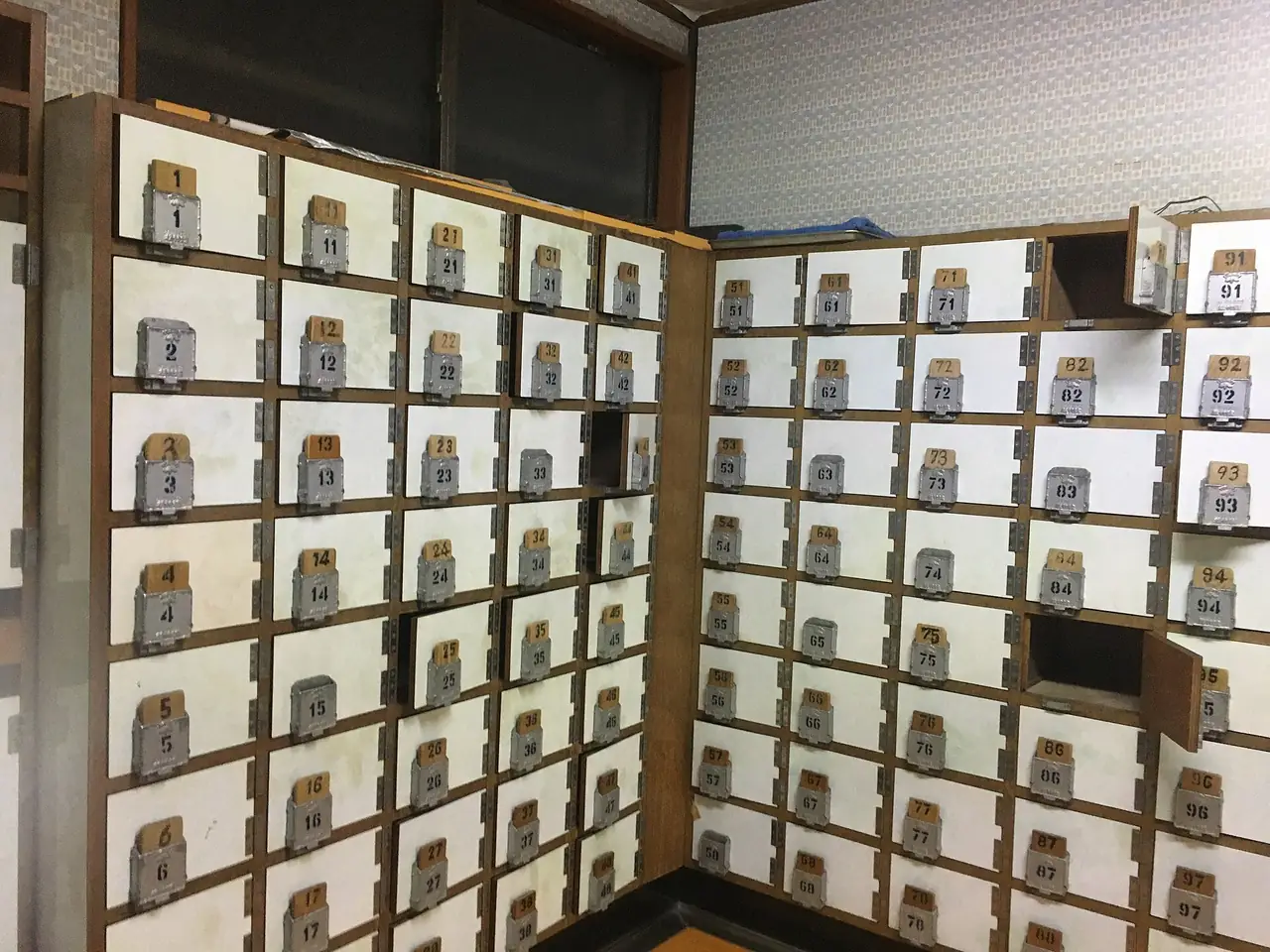 Numbered wooden shoe lockers with wooden keys inside the entrance of a Tokyo sento