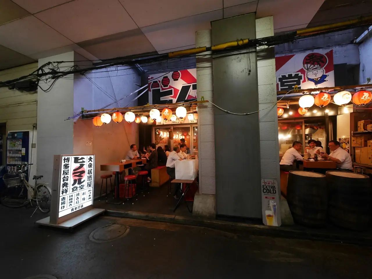 Lantern-lit bar with barrel tables under the railway tracks in Yurakucho