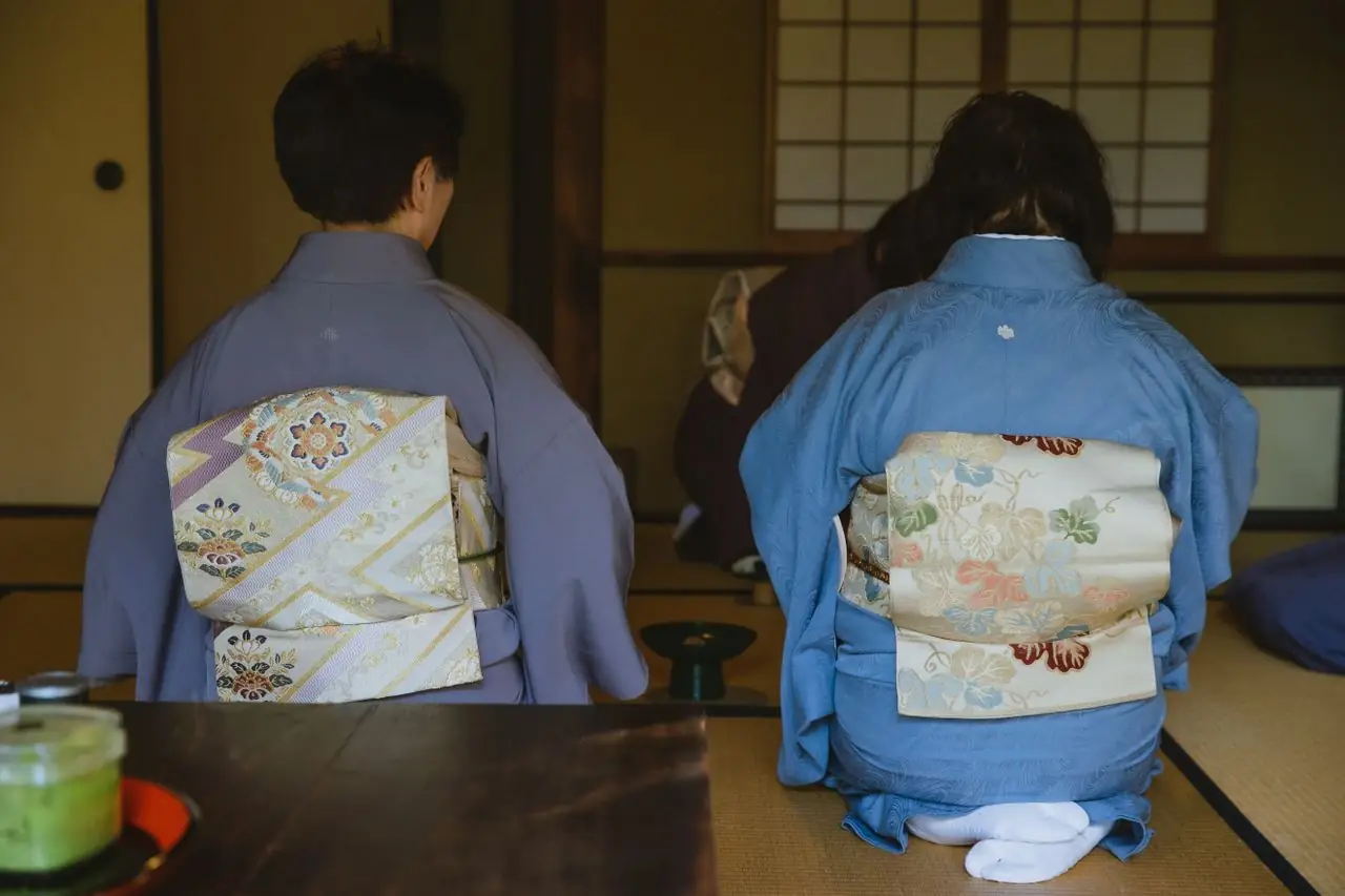 Guests in kimono kneeling on tatami during a traditional Japanese tea ceremony