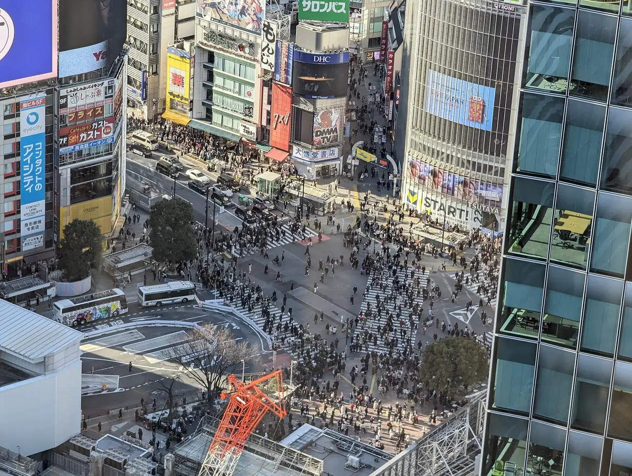 Crowds filling Shibuya Scramble Crossing seen from high above on a sunny afternoon