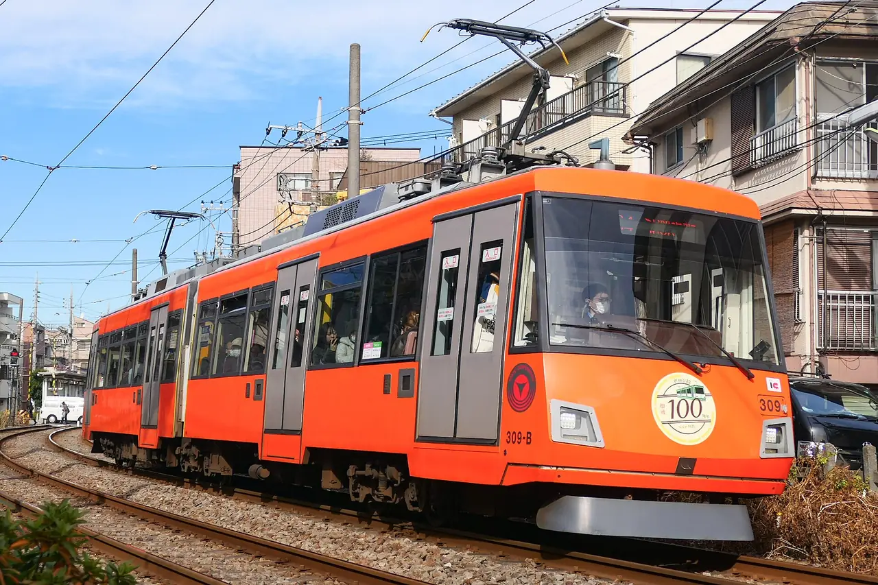 Orange Setagaya Line tram passing low-rise houses in residential Setagaya