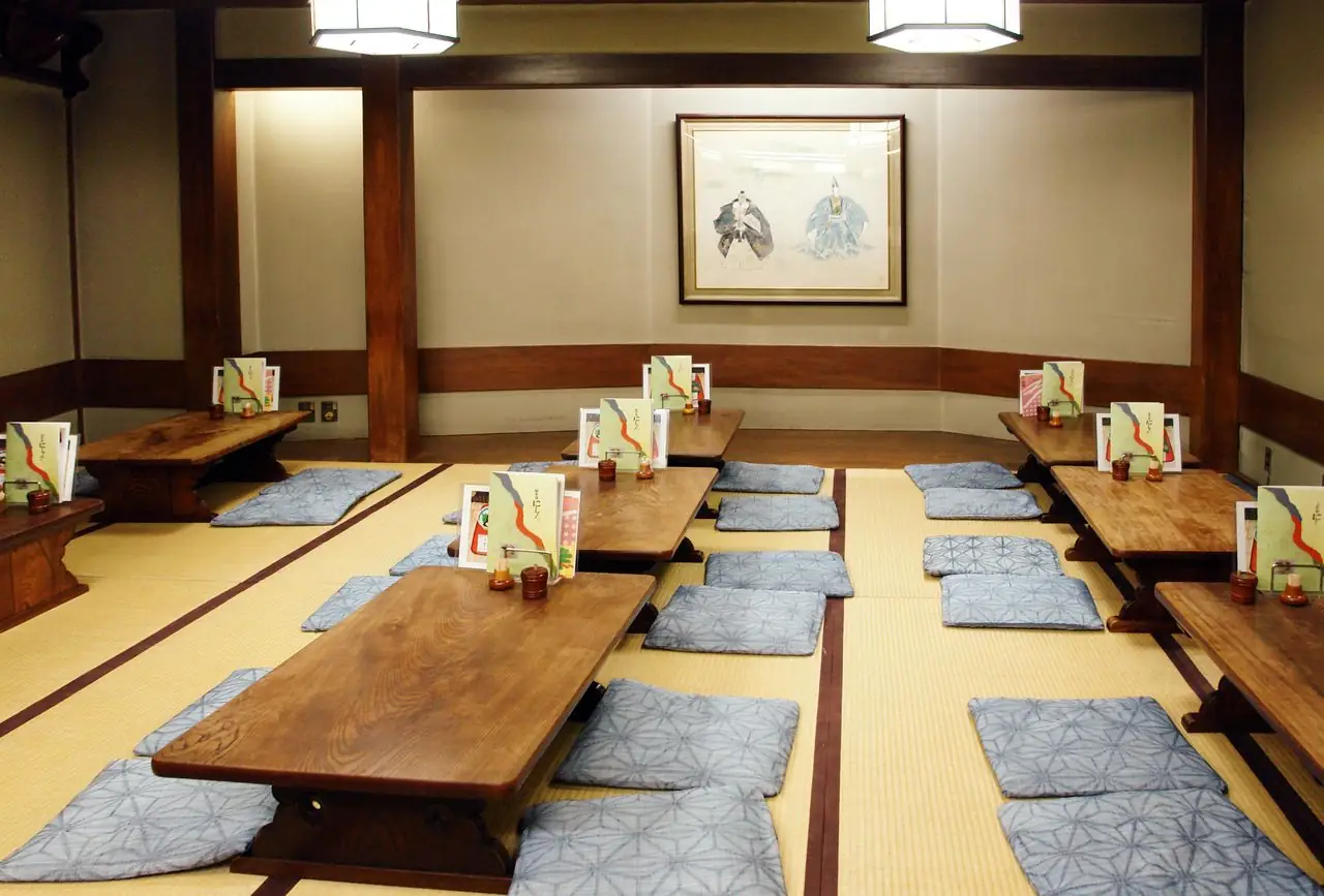 Tatami dining room with low tables and floor cushions laid out for a large group