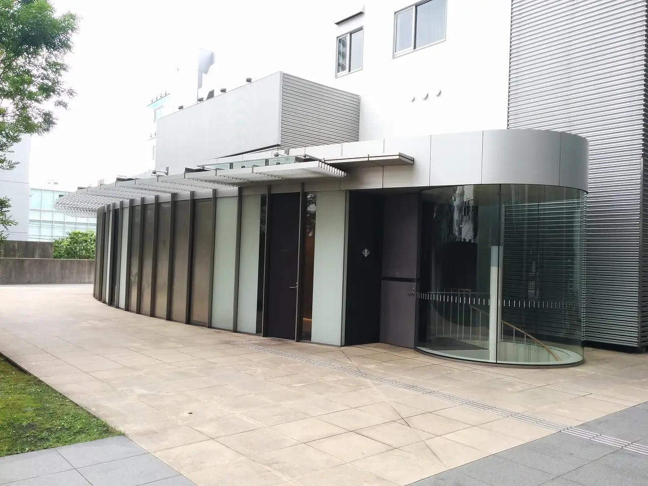 The curved glass and stone frontage of NARISAWA restaurant in Minami-Aoyama