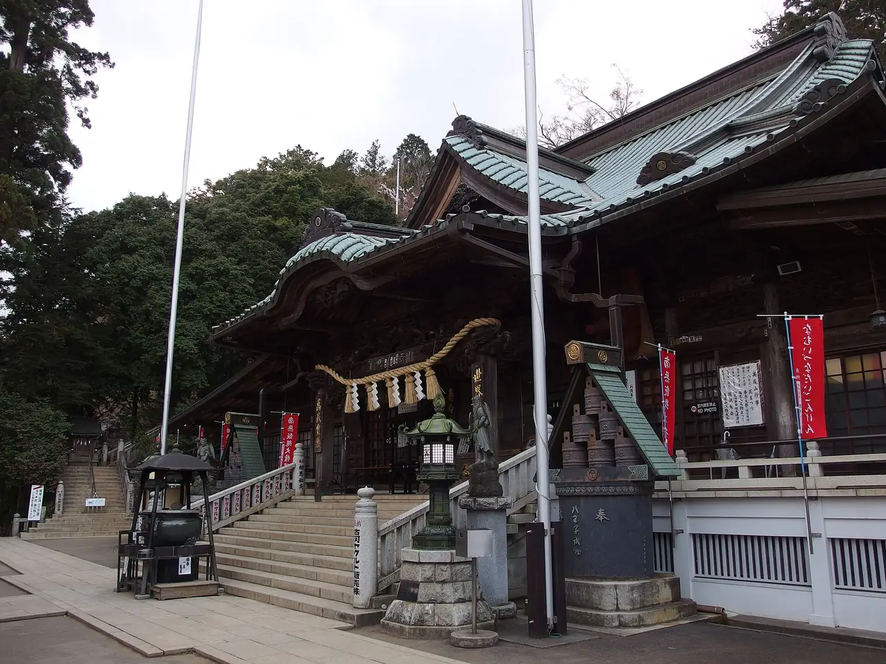 Ornate hall at Yakuo-in Temple on Mt Takao beside stone stairs and a lantern