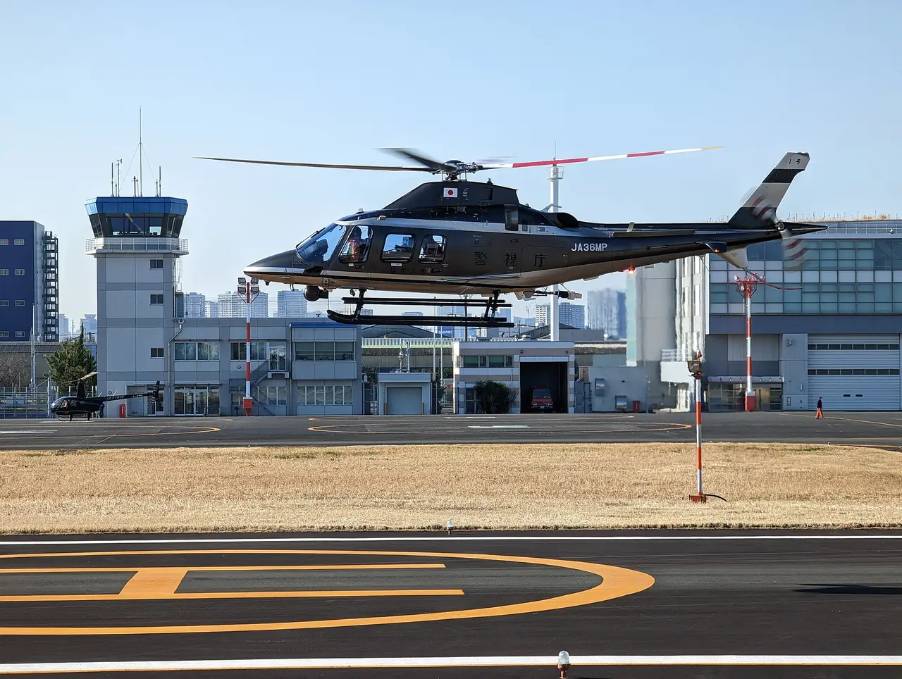 Tokyo Metropolitan Police helicopter landing past the control tower at Tokyo Heliport