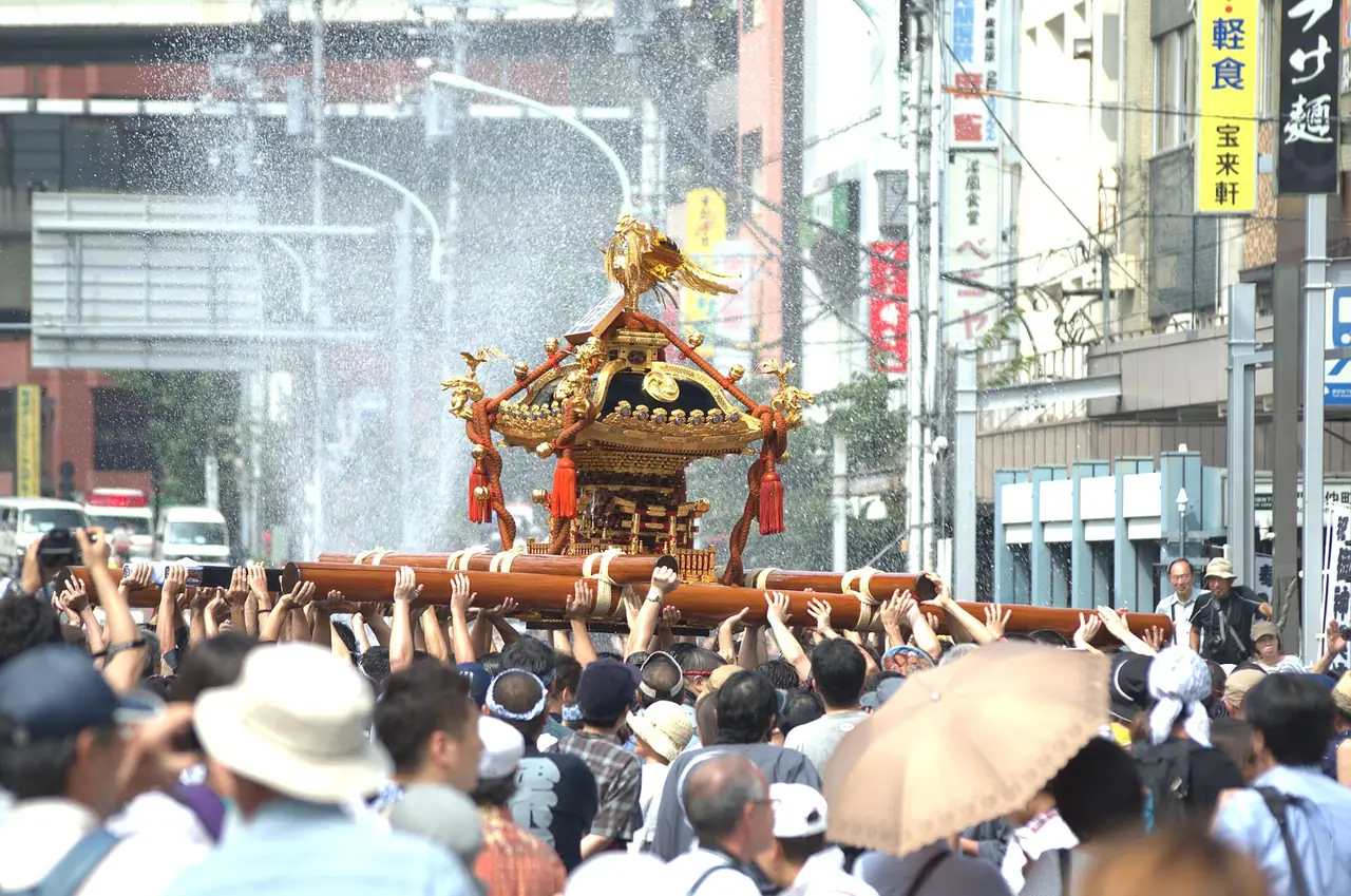 Crowd splashing water on a mikoshi near Monzen-Nakacho crossing during Fukagawa Hachiman Matsuri