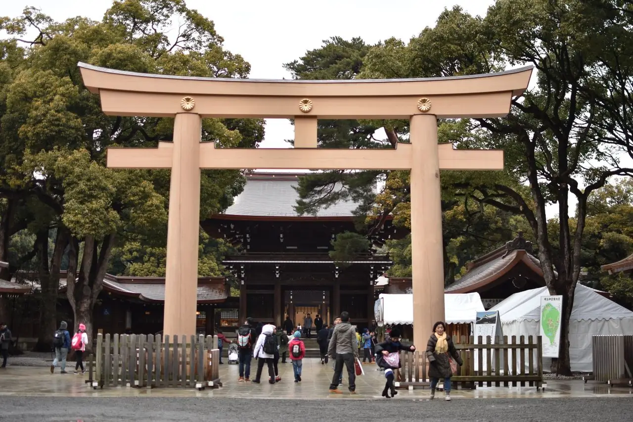 Visitors passing under the wooden torii in front of the Meiji Shrine main gate