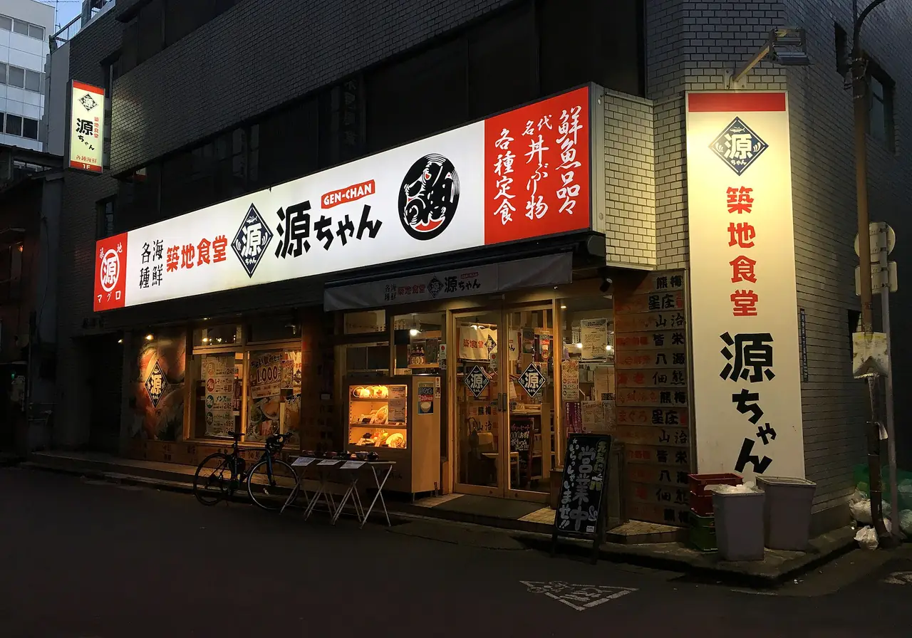 Lit signboards outside a Tsukiji Shokudo Gen-chan izakaya branch in Kanda at dusk