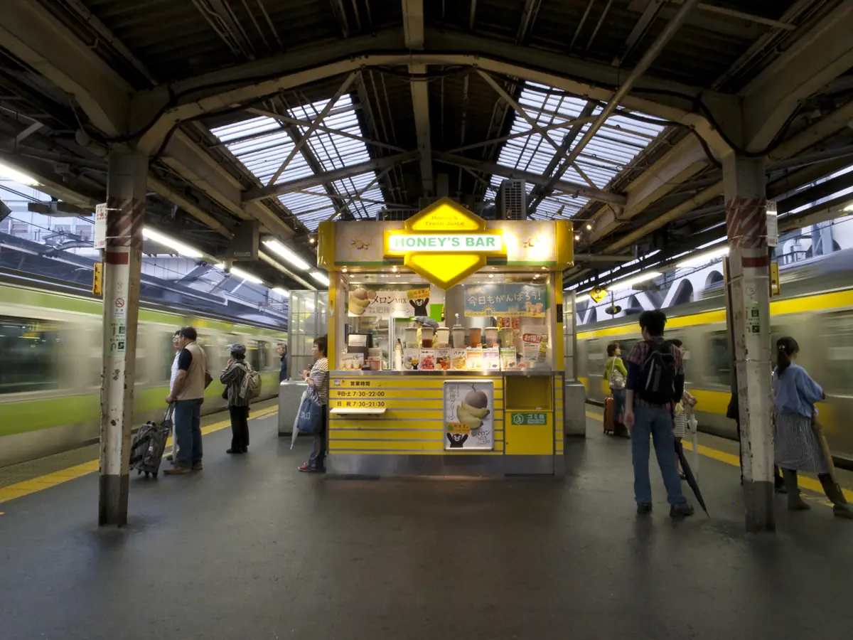 Passengers waiting by a kiosk on the Yamanote and Chuo-Sobu Line platform at Shinjuku Station