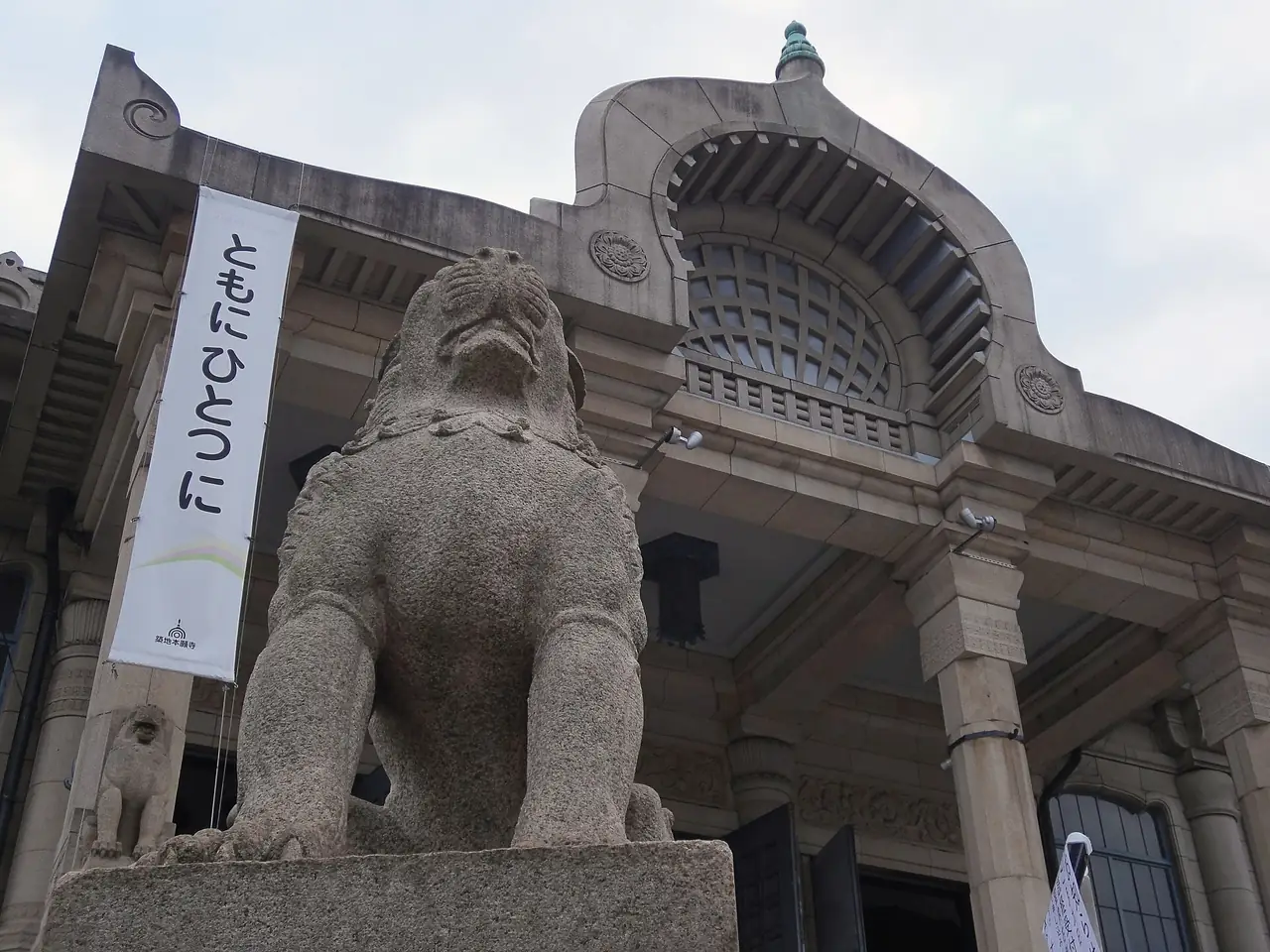 Carved stone guardian lion in front of the arched entrance of Tsukiji Honganji