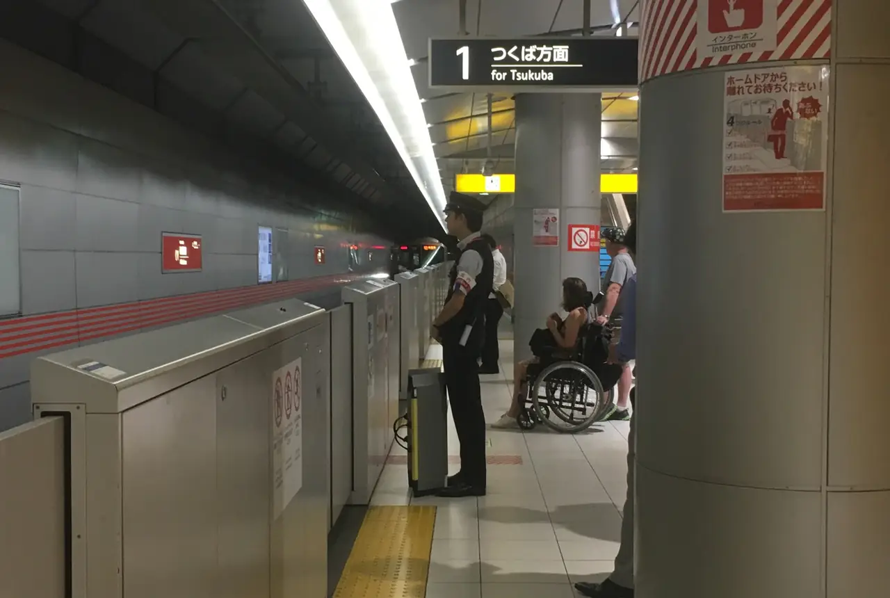 Station staff waiting with a wheelchair user on the Tsukuba Express platform at Akihabara